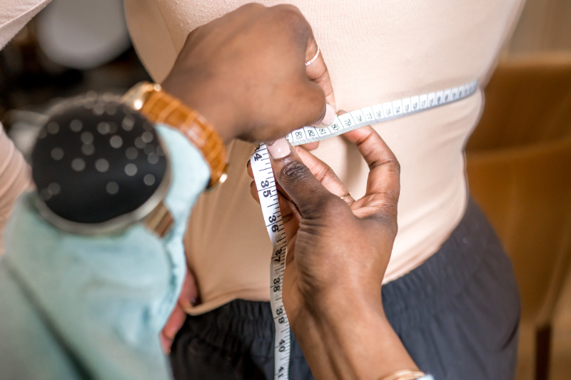 La créatrice prend les mensurations d'une cliente pour réaliser une commande spéciale de lingerie haut-de-gamme. Aime Couture propose des prestations lingerie telles que coffret nuptial, lingerie post-opération...